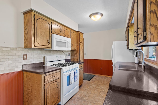 7830 Country Ln, Lino Lakes, MN 55014 - kitchen with white appliances, wainscoting, a sink, wooden walls, and dark countertops
