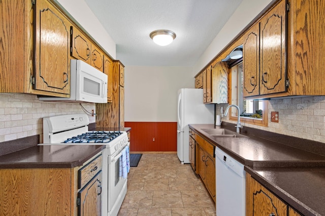 7830 Country Ln, Lino Lakes, MN 55014 - kitchen with white appliances, a sink, dark countertops, wainscoting, and backsplash