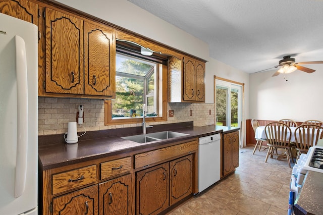 7830 Country Ln, Lino Lakes, MN 55014 - kitchen with white appliances, dark countertops, a sink, brown cabinetry, and a textured ceiling