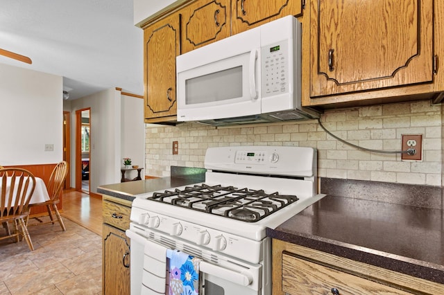 7830 Country Ln, Lino Lakes, MN 55014 - kitchen with white appliances, brown cabinets, dark countertops, wainscoting, and backsplash