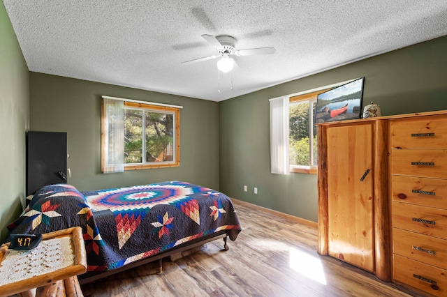 7830 Country Ln, Lino Lakes, MN 55014 - bedroom featuring wood finished floors, a textured ceiling, a ceiling fan, and baseboards