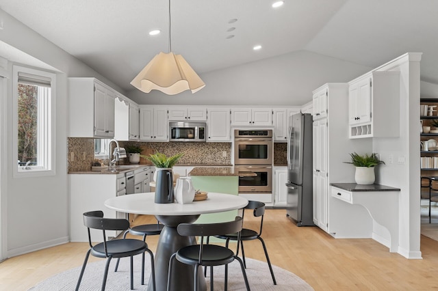 kitchen featuring light wood-style floors, stainless steel appliances, a sink, and backsplash
