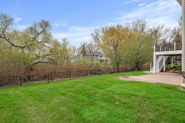 view of yard with a patio area, fence, and stairs