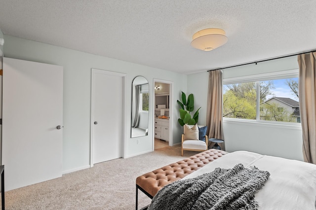 carpeted bedroom with ensuite bath and a textured ceiling