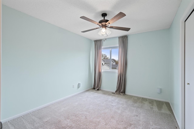 spare room with a textured ceiling, baseboards, ceiling fan, and carpet