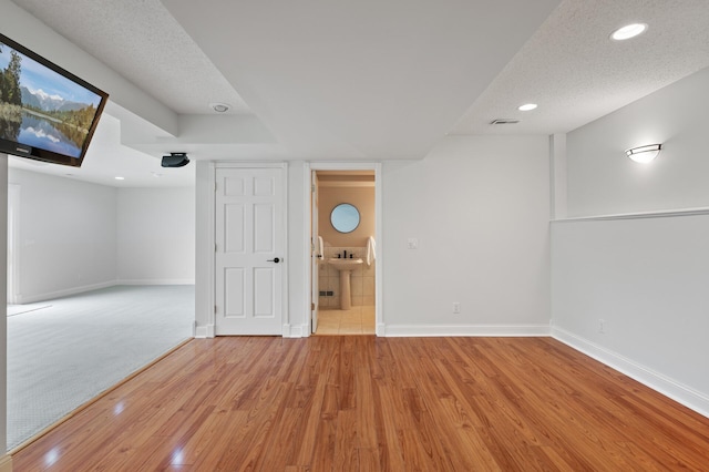 finished below grade area with baseboards, recessed lighting, a sink, and wood finished floors