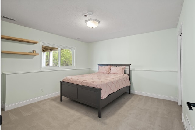 bedroom featuring baseboards, light carpet, visible vents, and a textured ceiling