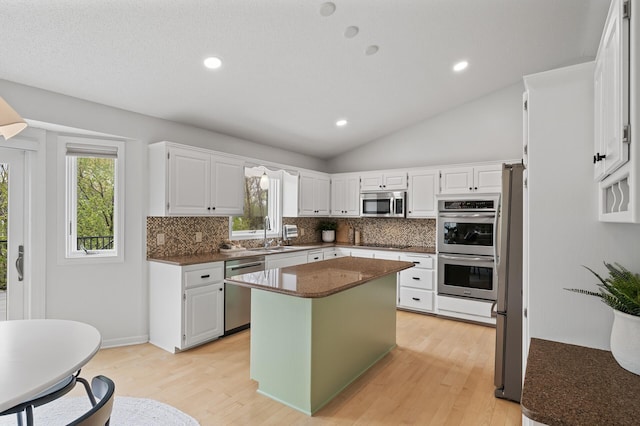 kitchen featuring light wood finished floors, stainless steel appliances, tasteful backsplash, and a sink