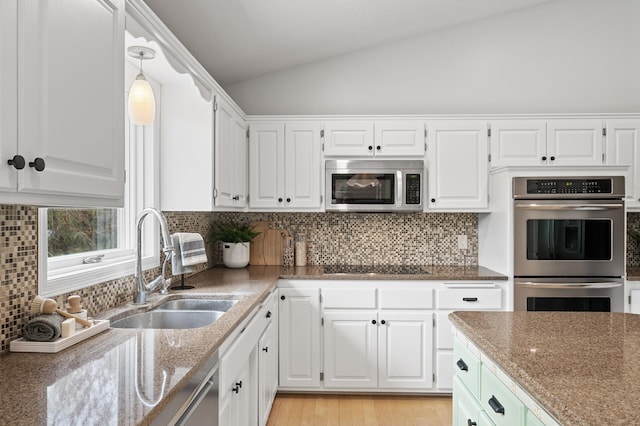 kitchen with dark stone counters, white cabinets, stainless steel appliances, and lofted ceiling