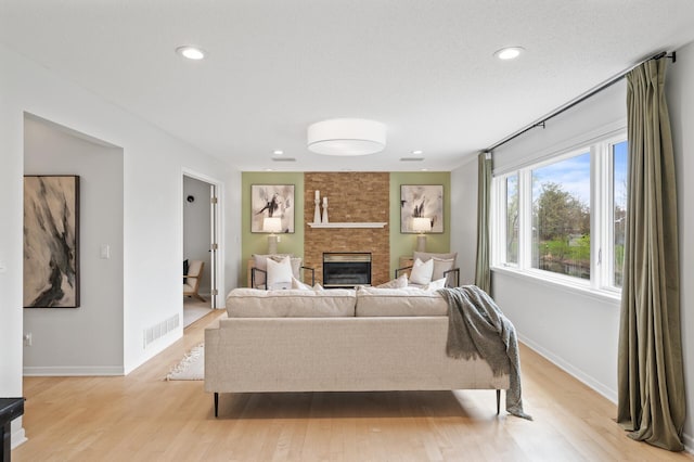 living room with light wood-type flooring, baseboards, a fireplace, and visible vents
