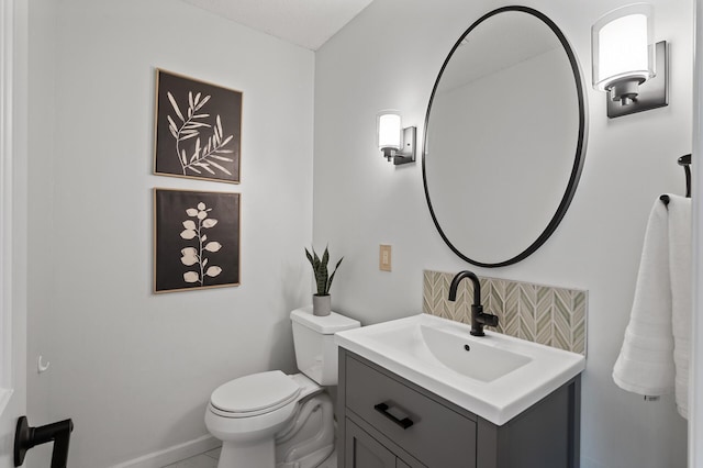half bathroom featuring toilet, baseboards, and vanity