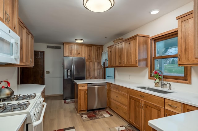 829 Church St, Saint Peter, MN 56082 - kitchen featuring appliances with stainless steel finishes, light wood-style floors, light countertops, a peninsula, and brown cabinets