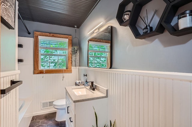 8 Queen Ave S, Minneapolis, MN 55405 - bathroom featuring a wainscoted wall, toilet, vanity, tile patterned floors, and tub / shower combination