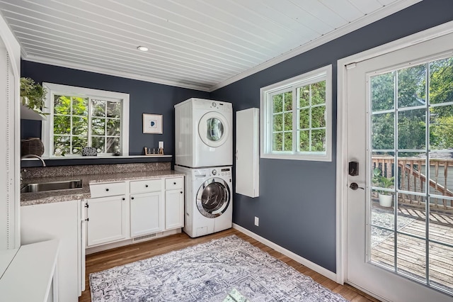 8 Queen Ave S, Minneapolis, MN 55405 - laundry room featuring stacked washing machine and dryer, cabinet space, crown molding, wood finished floors, and baseboards