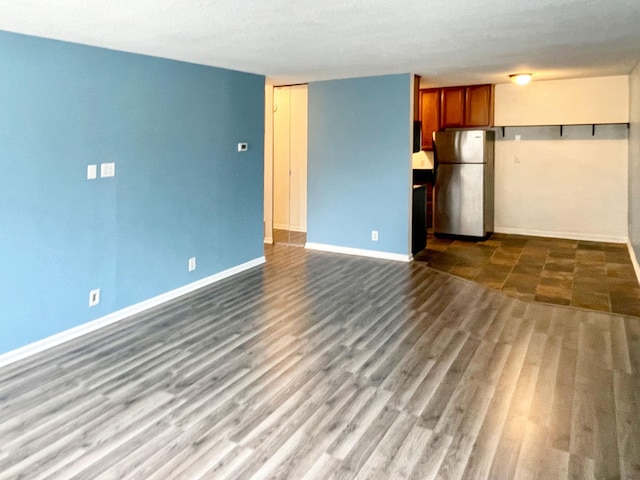 unfurnished living room featuring baseboards and dark wood-style flooring