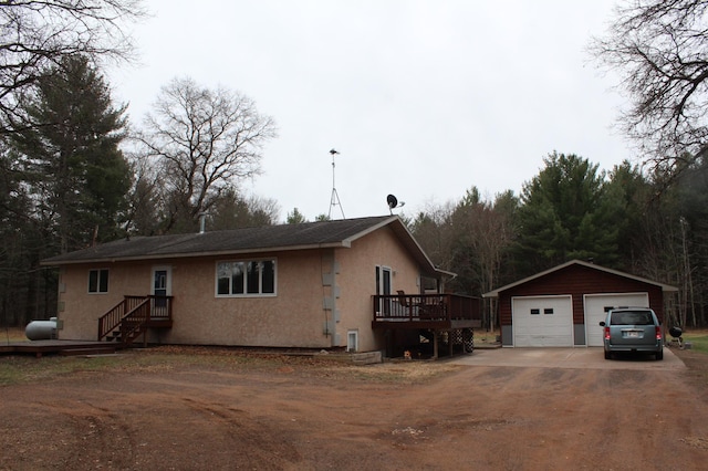14879 Benson Rd, Grantsburg, WI 54840 - view of front of house featuring stucco siding, a wooden deck, an outbuilding, and a garage