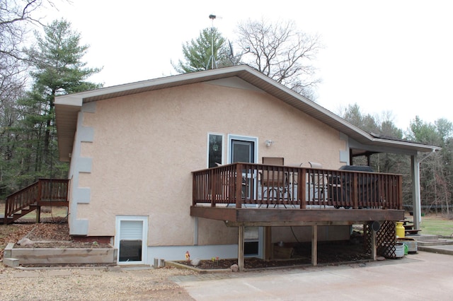 14879 Benson Rd, Grantsburg, WI 54840 - back of house with stairs, stucco siding, and a wooden deck