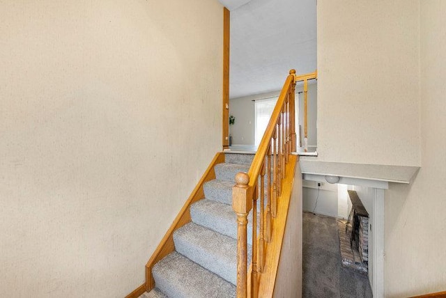 stairway featuring carpet floors, baseboards, and a fireplace