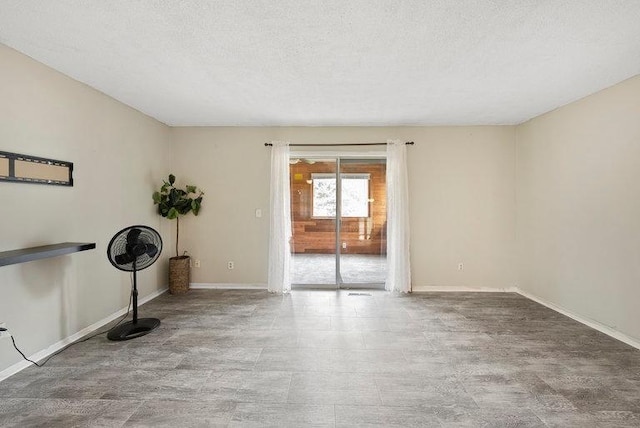 spare room with a textured ceiling and baseboards