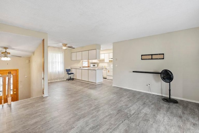 unfurnished living room with baseboards, ceiling fan, and wood finished floors