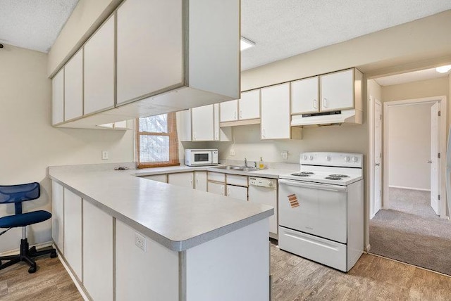 kitchen featuring light countertops, light wood finished floors, under cabinet range hood, and white appliances