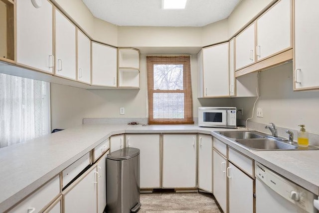 kitchen with white appliances, white cabinets, a sink, and light countertops