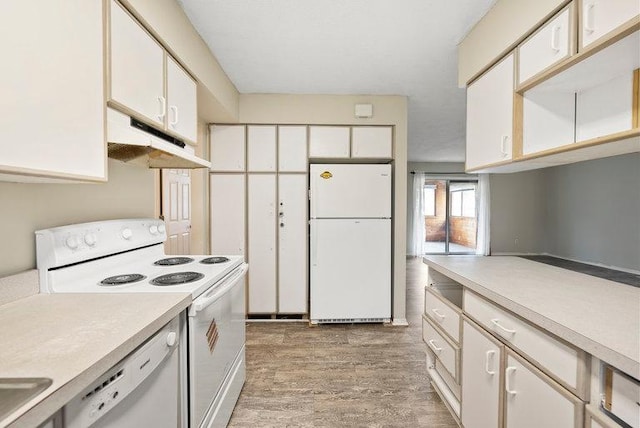 kitchen with white appliances, light wood-type flooring, light countertops, white cabinetry, and under cabinet range hood