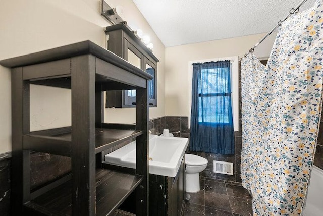 full bath featuring tile walls, toilet, curtained shower, and visible vents