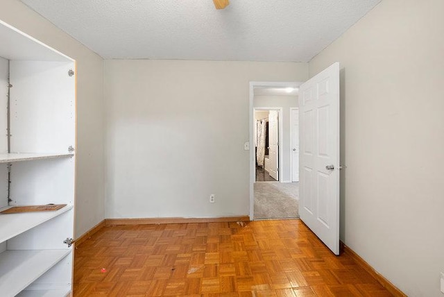 spare room featuring a textured ceiling and baseboards