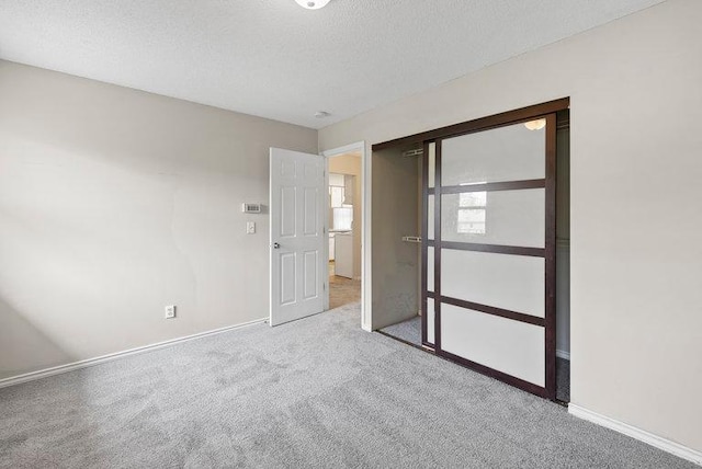 unfurnished room with baseboards, carpet flooring, and a textured ceiling