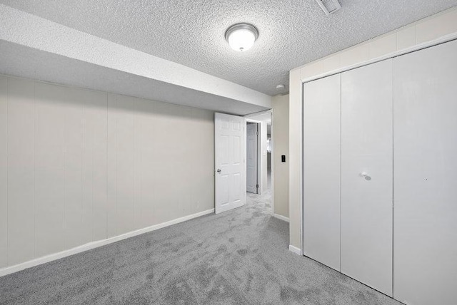 unfurnished bedroom featuring a textured ceiling, visible vents, baseboards, a closet, and carpet