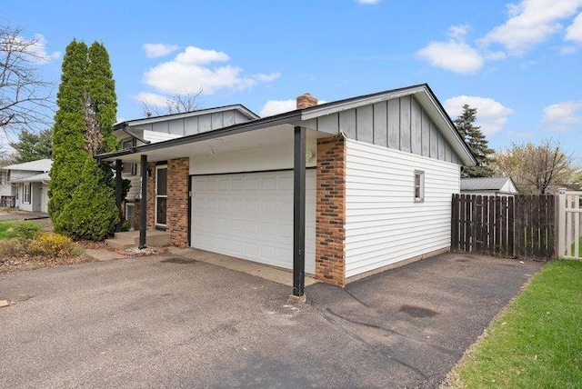 view of home's exterior featuring fence, board and batten siding, driveway, and brick siding