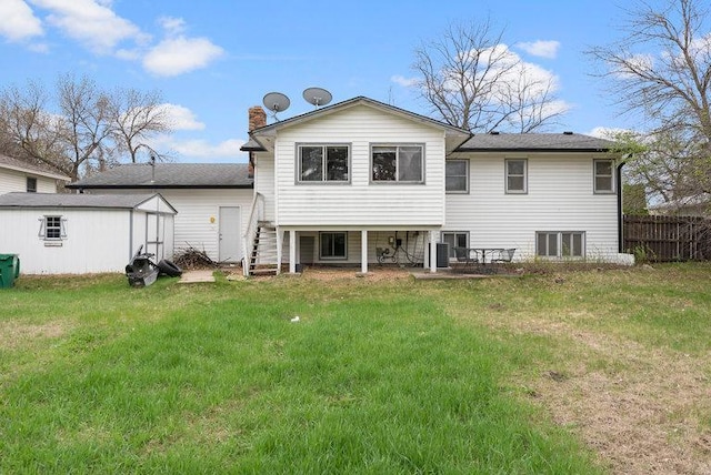 rear view of house with an outdoor structure, fence, a chimney, central AC unit, and a yard