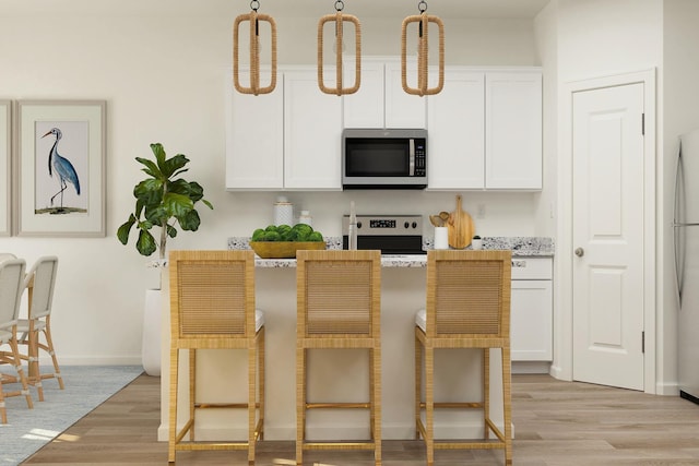 10213 Twin Lakes Pkwy NW, Elk River, MN 55330 - kitchen featuring stainless steel appliances, light wood-style floors, a breakfast bar, white cabinetry, and baseboards