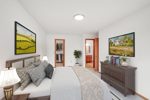 bedroom featuring light colored carpet, connected bathroom, a walk in closet, and a closet