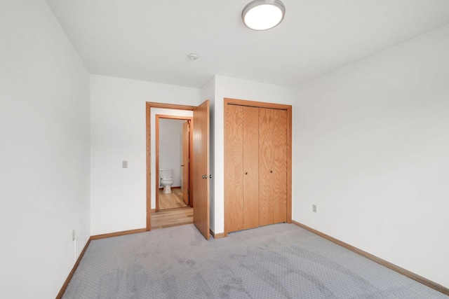 unfurnished bedroom with baseboards, carpet, and a closet