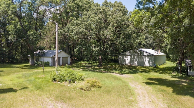 view of yard featuring an outbuilding, a garage, and a view of trees