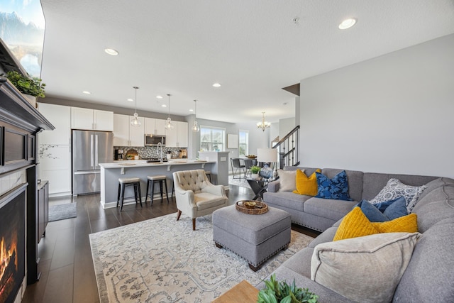 4343 Corn Silk Ln, Woodbury, MN 55129 - living area featuring a chandelier, a lit fireplace, recessed lighting, dark wood-type flooring, and stairs