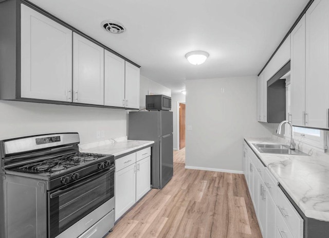 314 Orchard St N, Northfield, MN 55057 - kitchen with appliances with stainless steel finishes, a sink, light wood-type flooring, light stone countertops, and white cabinetry
