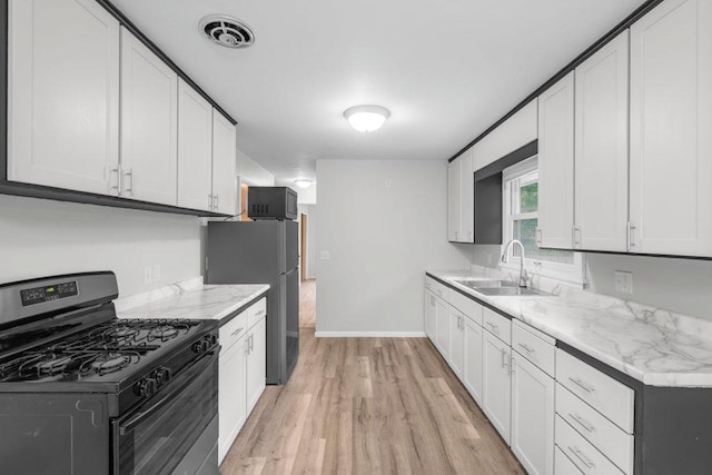 314 Orchard St N, Northfield, MN 55057 - kitchen with gas range oven, a sink, light wood-style floors, black microwave, and baseboards