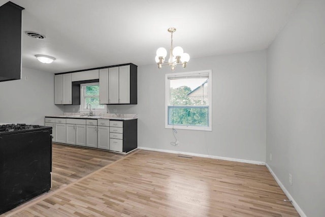 314 Orchard St N, Northfield, MN 55057 - kitchen with gas range oven, light wood finished floors, a sink, a chandelier, and baseboards