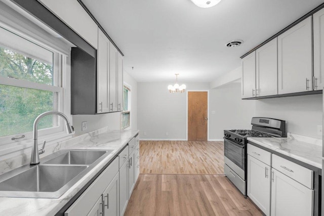 314 Orchard St N, Northfield, MN 55057 - kitchen with stainless steel range with gas cooktop, a sink, light wood-type flooring, a chandelier, and light countertops