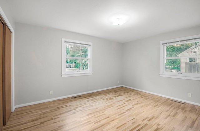 314 Orchard St N, Northfield, MN 55057 - unfurnished bedroom with light wood-style floors, multiple windows, a closet, and baseboards