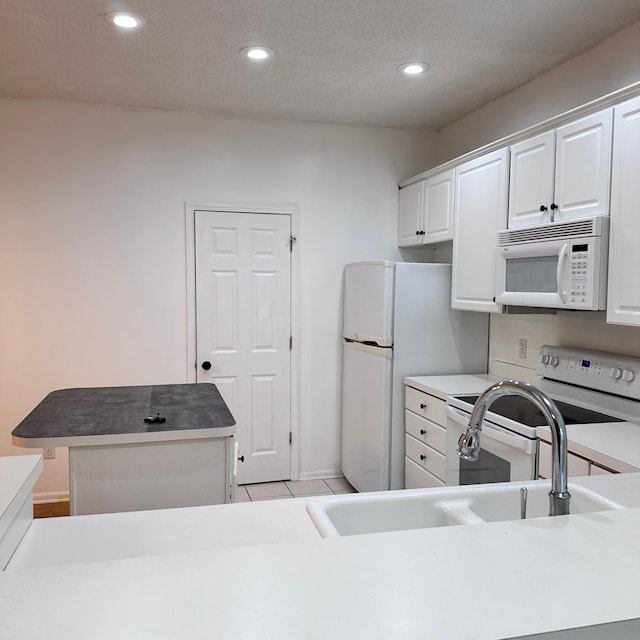 kitchen featuring white cabinets, a sink, a kitchen island, recessed lighting, and white appliances