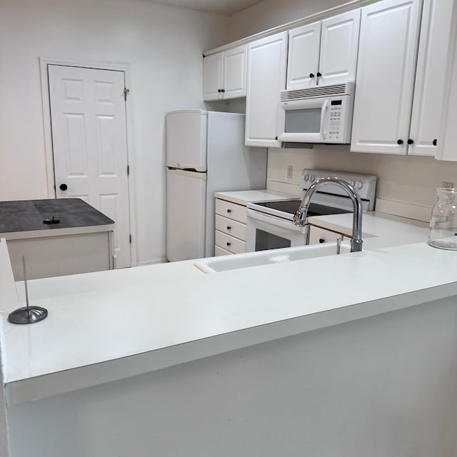 kitchen with light countertops, white cabinets, and white appliances