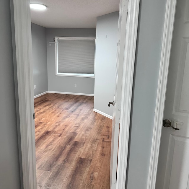 corridor featuring wood finished floors and baseboards