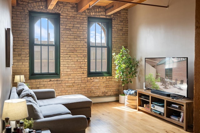 living area featuring brick wall, hardwood / wood-style flooring, a baseboard heating unit, baseboards, and beam ceiling