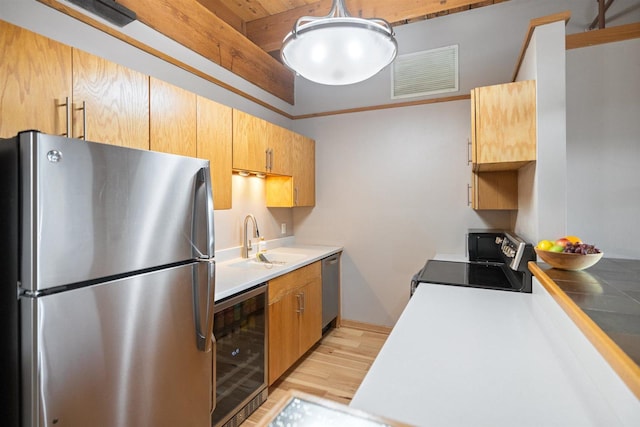 kitchen featuring stainless steel appliances, wine cooler, light wood-style floors, a sink, and light countertops
