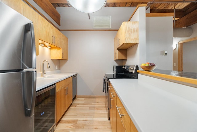 kitchen with stainless steel appliances, wine cooler, light wood-style floors, a sink, and light countertops