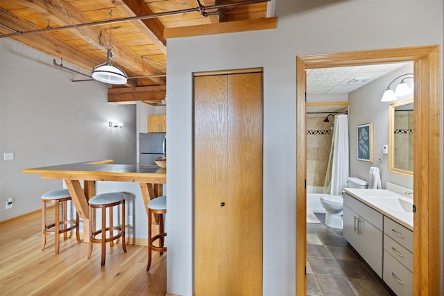 kitchen featuring wooden ceiling, freestanding refrigerator, beamed ceiling, a sink, and gray cabinets